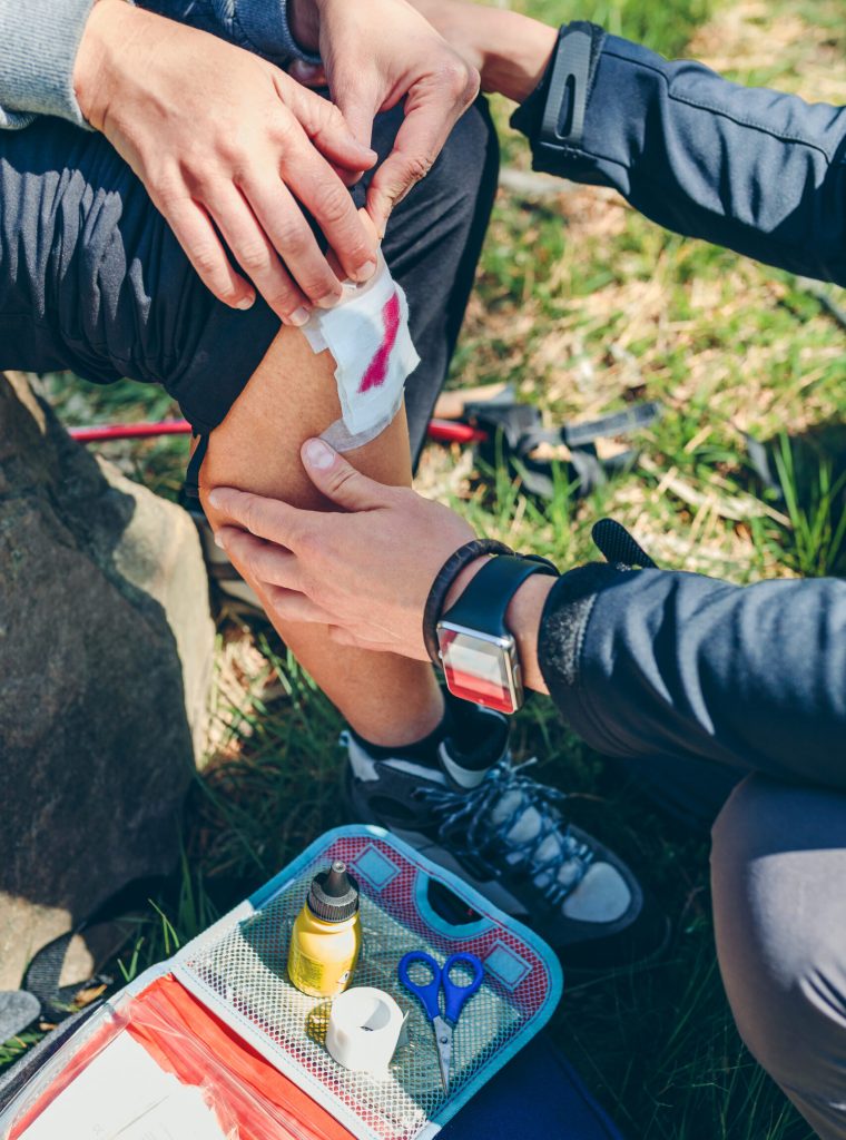 Young man healing knee to a young woman who has been injured doing trekking